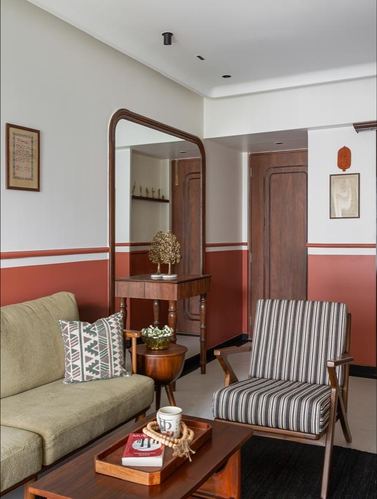 Living room corner with olive sofa, striped armchair, terracotta wall band and arched wooden mirror console
