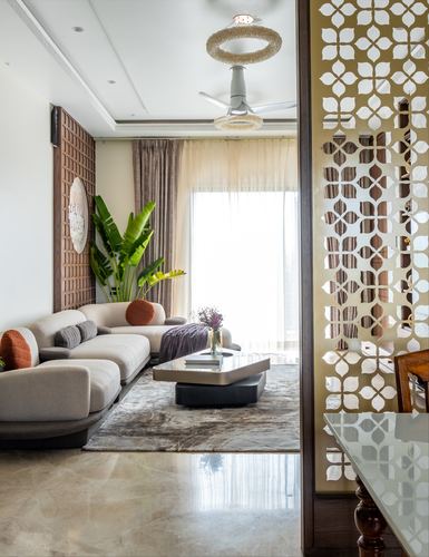 Living room with beige sofa, marble floor, and a carved floral jali partition screen