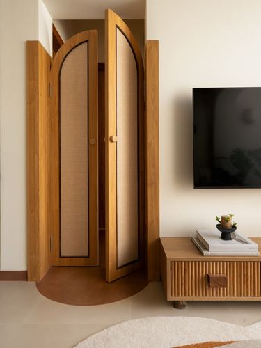 Arched wooden doors with cane panels beside a fluted wood tv console