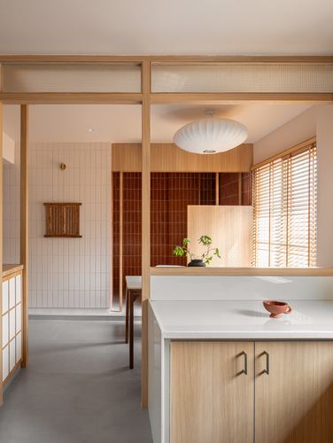 Wood-framed kitchen island opens to a tiled bathing area with terracotta tile wall beyond