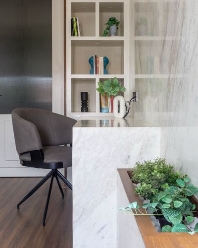 Marble waterfall desk edge beside built-in shelving and an indoor planter box