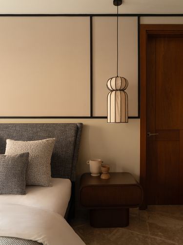 Bedroom corner with paneled wall, hanging lantern-style pendant, wooden bedside table and door