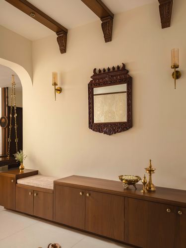 Foyer with carved wooden mirror, brass sconces, and wood console beneath beamed ceiling