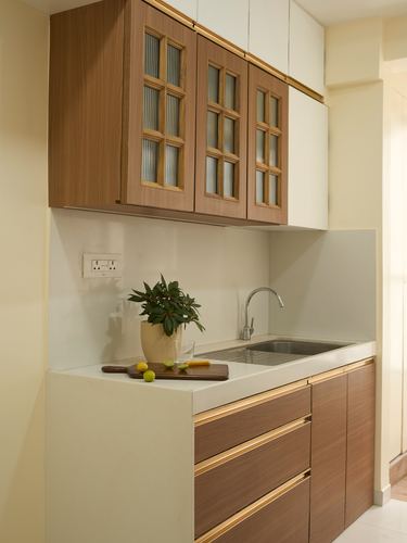 Compact kitchen with wood cabinetry, brass trim, glass-front upper cabinets and stone countertop