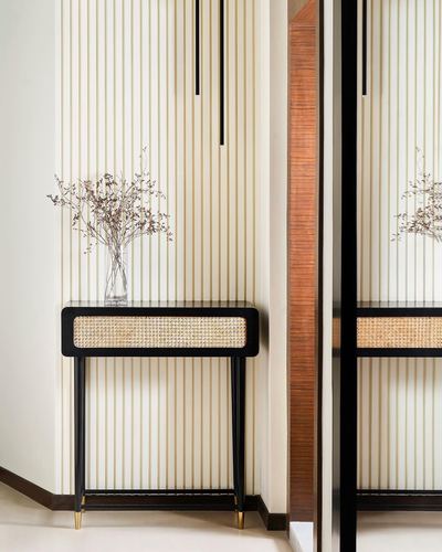 Cane-front console with dried flowers against a fluted cream wall in a foyer