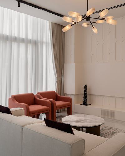 Living room with rust armchairs, sheer curtains, marble coffee table, and fluted plaster wall panel