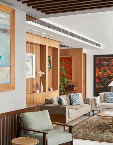 Living room with fluted wood paneling, framed art, sofas and a sage armchair on a patterned rug