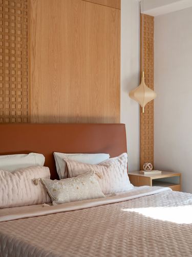 Bedroom corner with terracotta leather headboard, wood lattice paneling, and pendant lamp beside nightstand