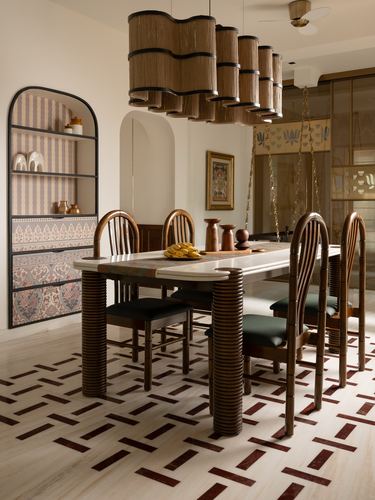 Dining room with ribbed wood table, woven pendant cluster, arched shelving and patterned marble floor