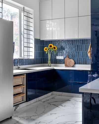 Blue and white kitchen corner with sunflowers, glossy navy cabinets and marble-look floor