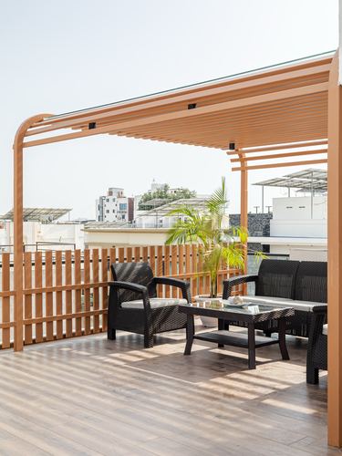 Rooftop terrace with wooden pergola, black rattan sofas, and city skyline view