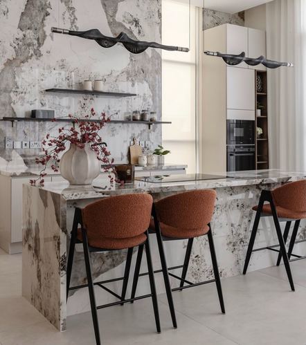 Dubai kitchen with bookmatched marble island, terracotta stools, and sculptural black pendant lights