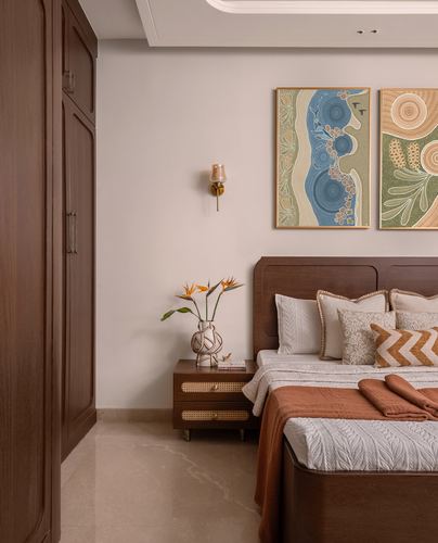 Bedroom corner with dark wood bed, cane nightstand, and paired abstract artworks above headboard
