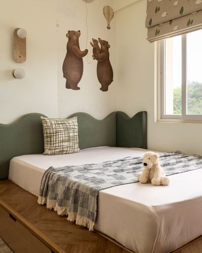 Child's bed with scalloped green headboard, bear decals, and window seat corner