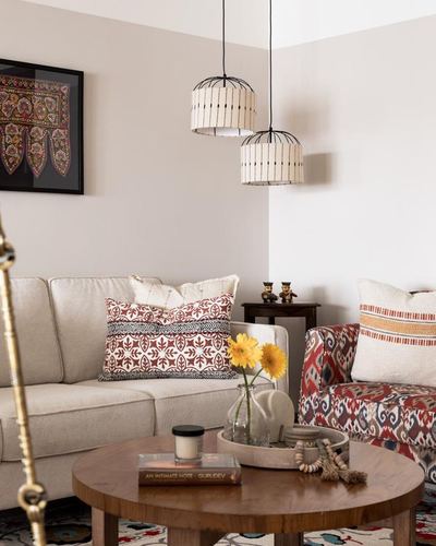 Living room corner with cane pendant lights, beige sofa, ikat armchair and round wood coffee table