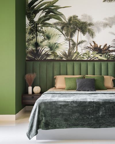 Bed with green fluted velvet headboard against tropical palm mural wallpaper and green wall