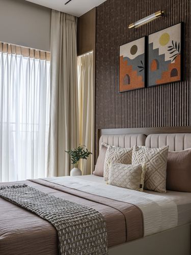 Bedroom with fluted wood wall, channel-tufted headboard, layered cushions and sheer curtained window