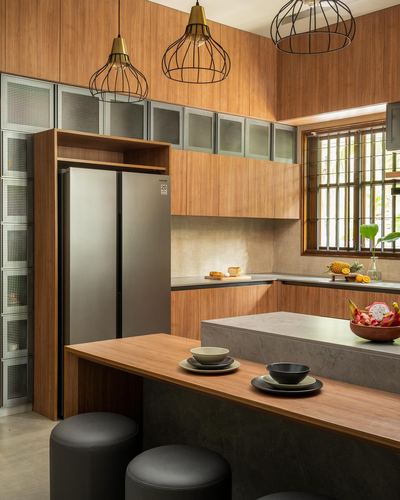 Wood-panelled kitchen with island, pendant lights, and steel refrigerator under tall ceiling