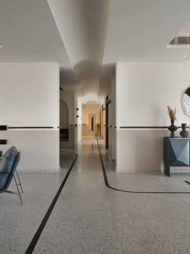 Long white corridor with curved ceiling and terrazzo floor featuring a black inlay line
