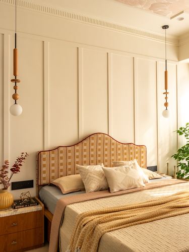 Bedroom with scalloped mustard headboard, wood pendant lights, and paneled cream wall