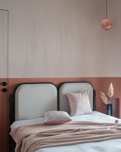 Twin arched headboards with pink and cream bedding against a fluted wall and terracotta base