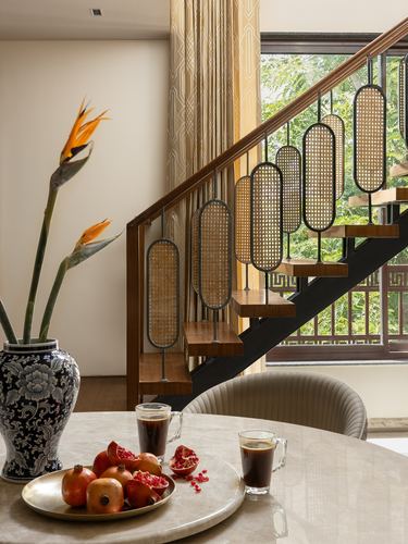 Staircase with cane oval balusters beside a marble table set with pomegranates and coffee