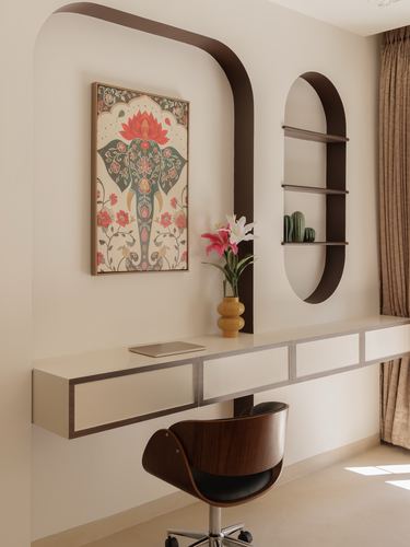 Floating desk under an elephant motif artwork with an arched brown frame and oval shelving niche