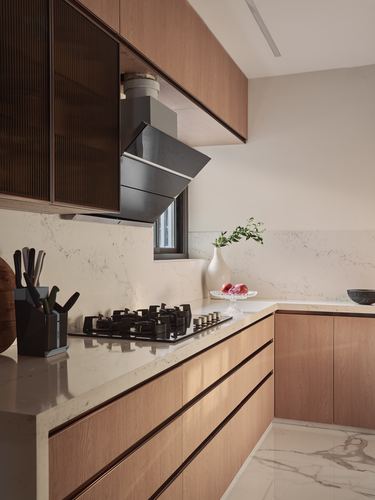 L-shaped kitchen with wood cabinetry, stone counters, black chimney hood over cooktop