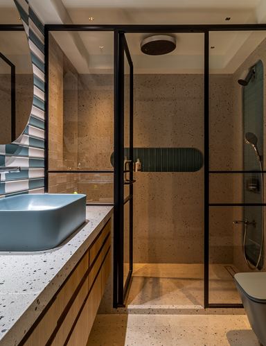 Bathroom with blue vessel sink, terrazzo counter, black-framed glass shower enclosure