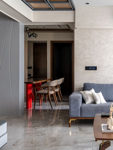 Living room with blue sofa, marble floor, and glimpse into dining area with red-lit table base