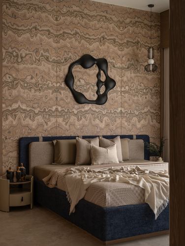Bed with navy upholstered frame against a patterned stone wall with a black organic mirror above