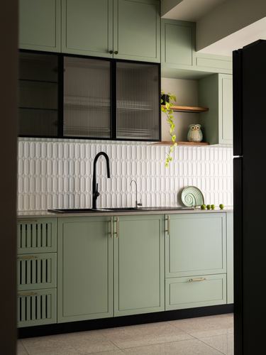 Sage green kitchen with sculpted white backsplash tile, black fixtures, and reeded glass cabinet door