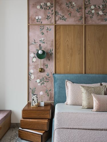 Bedroom corner with pink floral wallpaper, wood panelling, green sconce, wooden nightstand and teal upholstered bed.