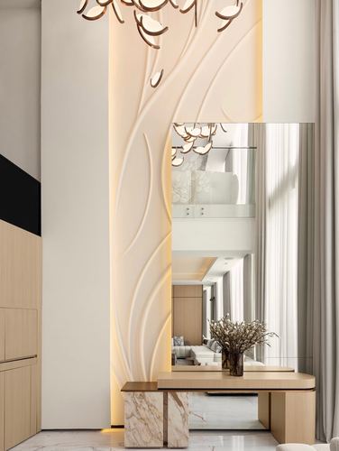 Double-height foyer with carved wall panel, sculptural pendant, mirror and marble-base console
