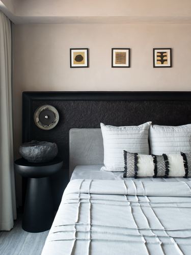 Bedroom with black textured headboard wall, layered white bedding, and framed art above