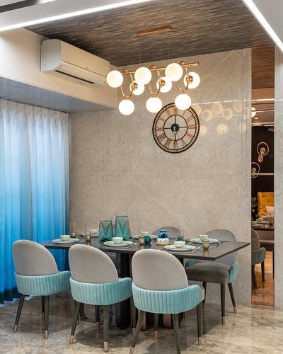 Dining room with teal velvet chairs, marble wall, globe chandelier, and large wall clock