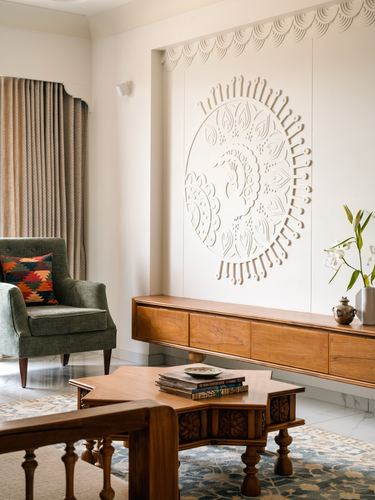Living room with carved circular plaster relief above a wooden console and star-shaped coffee table.