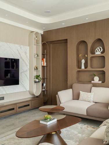 Living room with curved wood shelving, arched wall niches, marble tv wall, and beige sofa