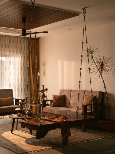 Living room with two hanging swings, wooden coffee table and sofa lit by warm afternoon light