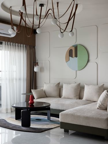 Living room with beige sectional, round wall art, black oval table, and layered chandelier