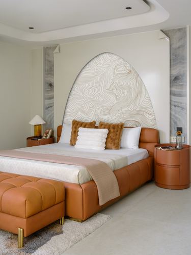 Bedroom with tan leather bed, arched wood-patterned headboard panel, and round leather nightstands