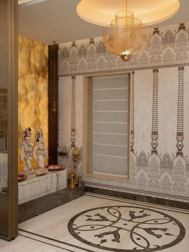 Pooja room with backlit onyx wall, marble idols, brass diya stand, and inlaid marble floor medallion