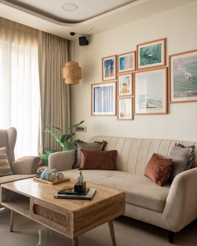 Beige living room with sofa, wooden coffee table, and framed ocean-themed gallery wall