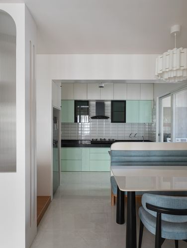 View through foyer into a mint-green and white kitchen with dining seating in foreground