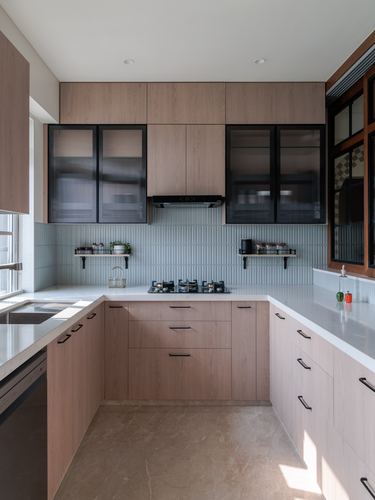 U-shaped modern kitchen with wood cabinetry, fluted glass uppers, pale blue tiled backsplash, and stone countertops