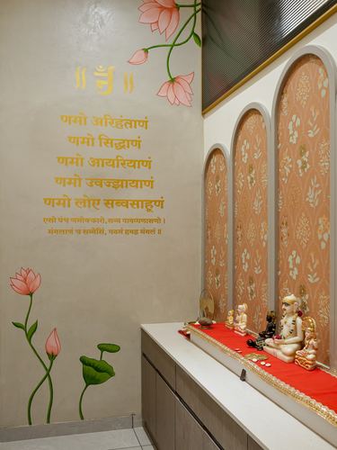 Pooja room with painted lotus mural, arched niches, and marble idols on red cloth
