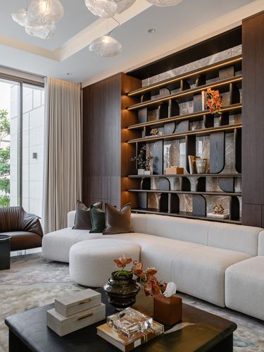 Living room with backlit arched shelving, dark wood paneling, cream sofa, and sculptural glass pendant lights