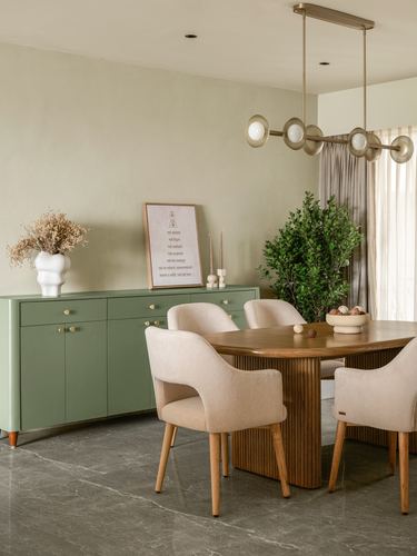 Dining room with sage green sideboard, fluted wood table and cream upholstered chairs