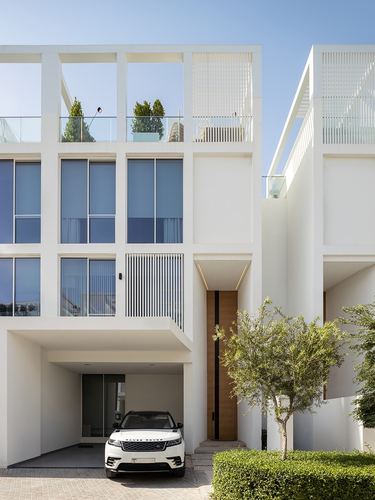 White minimalist villa facade with timber front door, carport, and parked SUV in Dubai