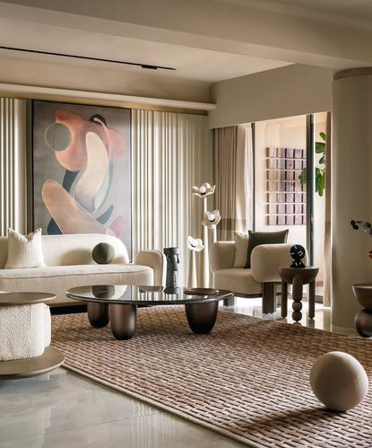 Neutral living room with boucle sofa, sculptural coffee tables, and abstract painting on fluted wall